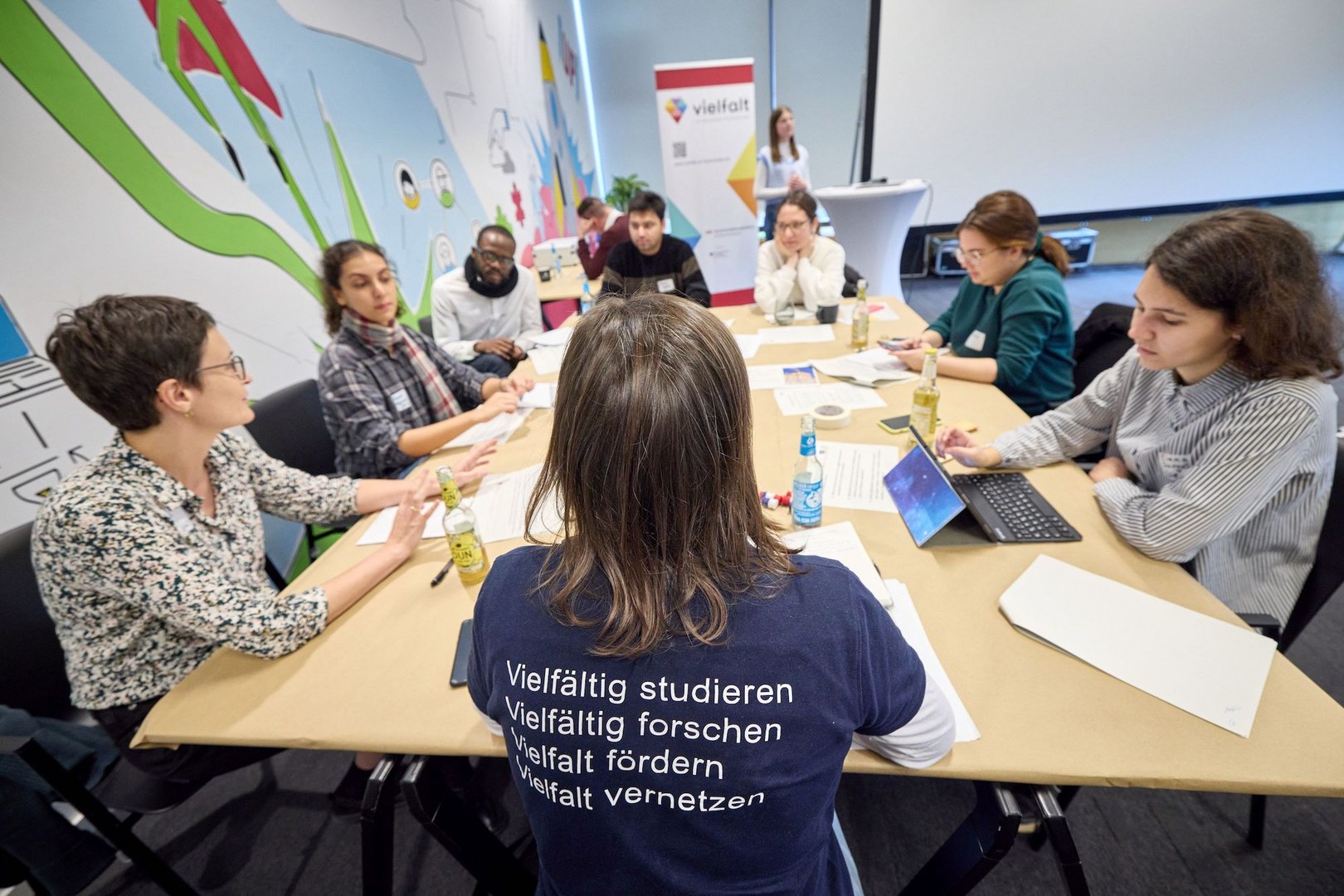 Photo of a group of participants in a workshop discussion sitting around a table and discussing