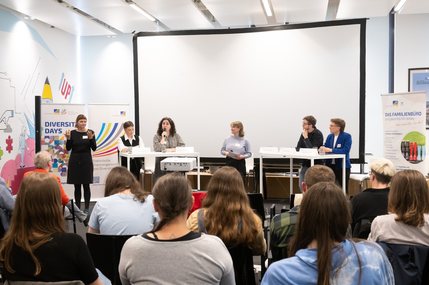Foto des Panels mit den vier Teilnehmenden, der Moderatorin und der Übersetzerin